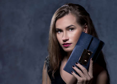 Positive emotional portrait of young and pretty girl. Portrait of beautiful woman holding a stylish clatch. Bags accessories advertising conceptの写真素材