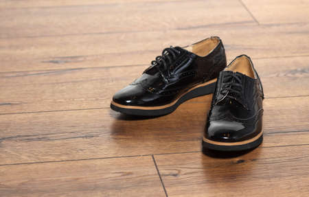 Close up of stylish female shoes boots.  Stylish fashion shoes boots footwear concept on brown wooden background. Urban footwear advertising on woodの写真素材