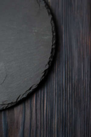 round black slate board on dark wooden tableの写真素材