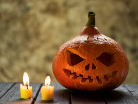 Festive scary halloween pumpkin on wooden table with candleの写真素材