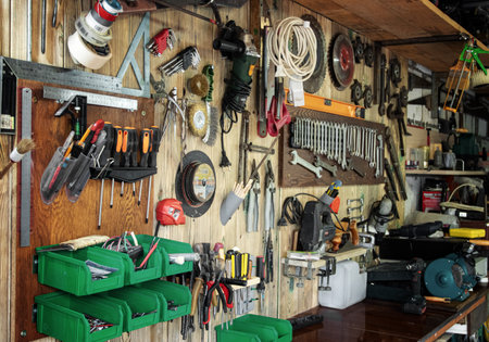 Various tools hang on a wooden wall in a workshop