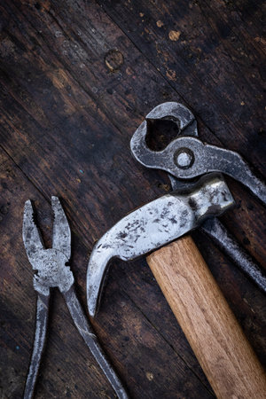 Old pliers, hammer and pincers on an old wooden workbench. Old work toolsの写真素材