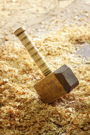 A carpenters wooden mallet lies on a workbench in wooden shavings
