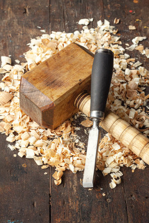Carpenters wooden mallet and chisel lie on a workbench with wood shavingsの写真素材