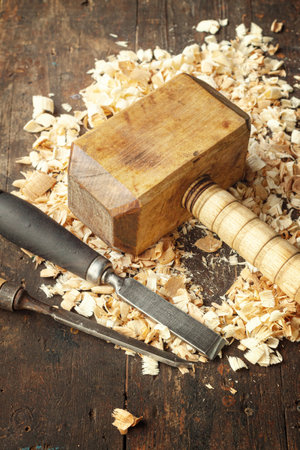 Carpenters wooden mallet and chisel lie on a workbench with wood shavingsの写真素材