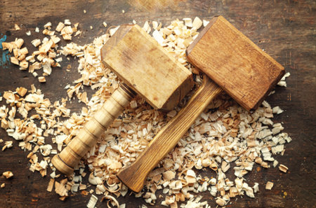 Two carpentry wooden mallets lie on a workbench with wood shavingsの写真素材