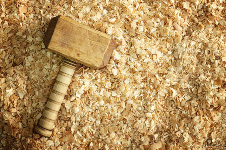 A carpenters wooden mallet lies on a workbench in wooden shavingsの写真素材