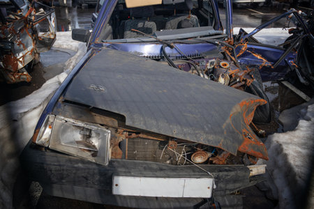 Broken and burnt cars after road accidents stand in a special parking lot