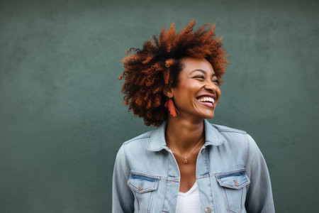 Portrait of a happy african american woman laughing against green backgroundの素材