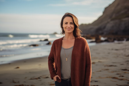 Portrait of a smiling woman standing on the beach at the sunsetの素材