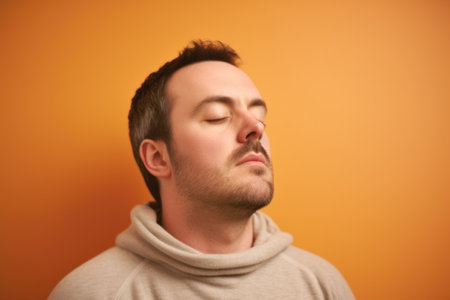 Portrait of a young man with closed eyes on an orange backgroundの素材