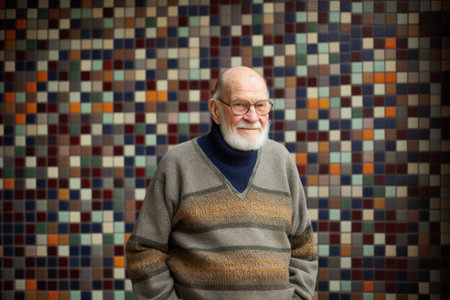 Portrait of a smiling senior man with glasses against a mosaic wallの素材