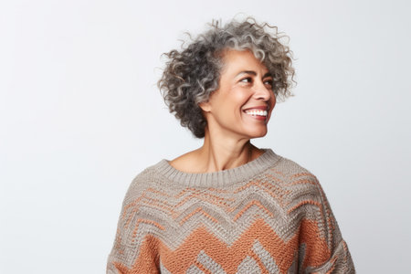 Portrait of a happy middle-aged woman with gray curly hair smiling over white backgroundの素材