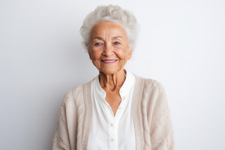 Portrait of a smiling senior woman looking at camera over white backgroundの素材