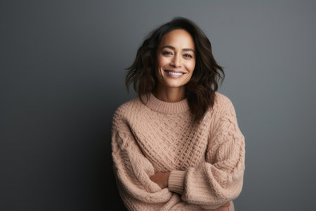 Portrait of smiling young woman in sweater looking at camera isolated on gray backgroundの素材