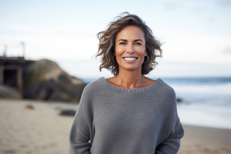 Portrait of beautiful woman smiling at camera on beach during autumn dayの素材