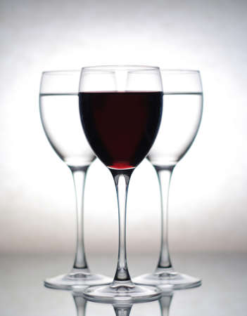 three wine glasses, one filled with wine and two others with waterの写真素材
