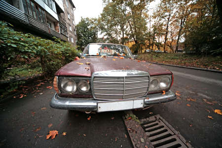 Old damaged sedan on the city street