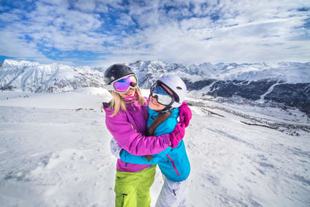Female skiers hugging on a snowy alps mountain slopeの写真素材