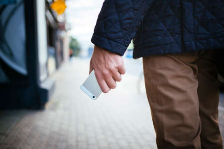 Cellphone in human palm on the city street blured backgroundの写真素材
