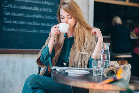 Young blonde woman drinking coffee cup background lifestuleの写真素材