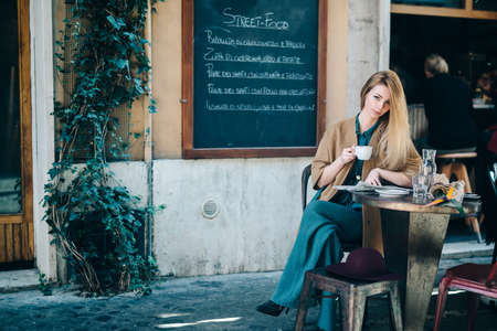 Restaurant table young woman drinking coffee blackboard backgroundの写真素材