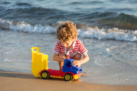 young boy playing with toys at the beachの写真素材