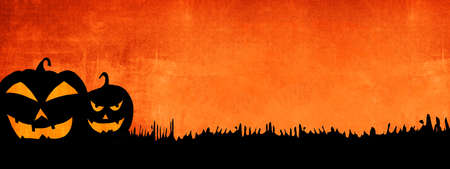HALLOWEEN background banner wide panoramic panorama template -Silhouette of scary carved luminous cartoon pumpkins isolated on dark orange night textureの写真素材