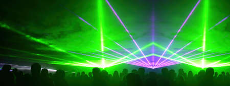 Lasershow festival disco party background banner panorama - Colorful outdoor laser show with rays streams and crowd silhouette of party peopleの写真素材