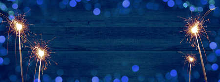 Frame of lights bokeh golden flares and sparkler isolated on rustic abstract blue wooden texture - Holiday New Year's Eve Silvester New Year Party festive background banner greeting cardの写真素材