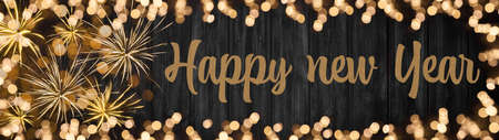 HAPPY NEW YEAR / Silvester 2022 New Year background panorama long - Golden Firework Fireworks and frame made of bokeh lights on rustic black wooden wood textureの写真素材