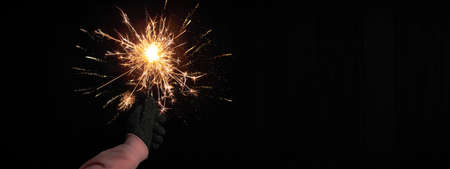 Silvester Party / New Year celebration festive background banner - Young happy pretty woman holding a sparkling sparkler in her hand at dark night sky.New Year's Eveの写真素材