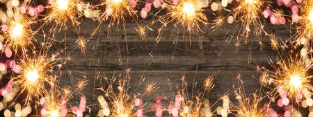 Frame made bokeh lights, sparklers and fireworks isolated on rustic wooden table texture - holiday...