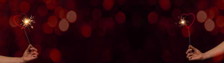 Valentine's Day / Love / Wedding / Birthday / Silvester / New Year / Party background - happy woman hold heart sparkler in her hands, at night with red bokeh lights, New Year's Eveの写真素材