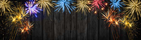 Silvester party, Happy New year Fireworks background banner panorama long- Firework, sparklers and bokeh lights on rustic black wooden texture, with space for textの写真素材