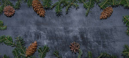 Frame of natural fir pine branches and cones on rustic dark black gray wooden table - christmas...