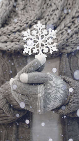 Merry Christmas / Winter snow background portrait format - Close-up of young woman with gloves and scarf holding a ice crystal in her hands, with snowy snowflakesの写真素材