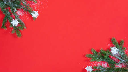 Festive decorative Christmas / Advent background - Fir branches, snowflakes and ice crystals, isolated on red paper texture, top view / above view with space for textの写真素材