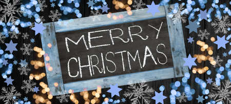 Merry Christmas background banner template - Top view from Chalkboard, bokeh lights, stars and ice crystals, isolated on dark black rustic wooden boards wall textureの写真素材
