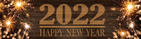 HAPPY NEW YEAR 2022, golden bokeh flares and sparkler isolated on rustic brown wooden texture -...