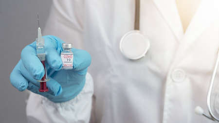 CORONAVIRUS COVID-19 / CORONA VACCINATION - Close-up from young female doctor holds syringe and bottle Corona vaccine in her handsの写真素材