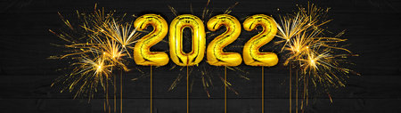 Gold foil balloons numeral 2022 and golden firework on dark black wooden texture - HAPPY NEW YEAR - Festive silvester New Year's Eve Party background panorama greeting card banner longの写真素材
