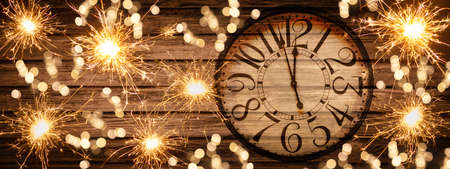 HAPPY NEW YEAR 2022 - Festive silvester New Year's Eve Party celebration background panorama banner long - Golden yellow fireworks, sparklers and clock on rustic brown wooden wall texture in the nightの写真素材