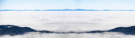 Sea of fog and snowy mountains in the background - Amazing mystical rising fog sky forest snow trees landscape in black forest ( Schwarzwald ) winter, Germany panorama - mystical winter snow moodの写真素材