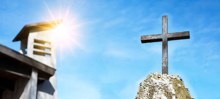 Religious Background - Blue sky with old weathered cross on rock on cemetery or church, illuminated...