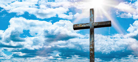 Religious Background - Old steel cross with blue sky, clouds and sunbeamsの写真素材