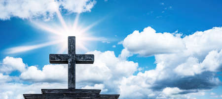 Religious Church Symbol Easter Background - Old steel cross with blue sky, clouds and sunbeamsの写真素材