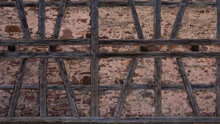 Old half-timbered wall lined with bricks or stones, texture of wall of rustic traditional barn background templateの写真素材