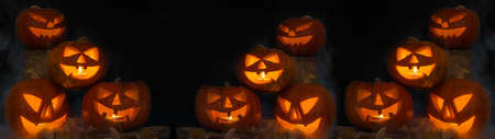 Scary Halloween celebration holiday background banner panorama - Spooky carved pumpkins and dust in the dark black nightの写真素材