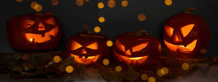 Scary Halloween celebration holiday background banner panorama - Spooky carved pumpkins and dust in the dark black night with bokeh lightsの写真素材